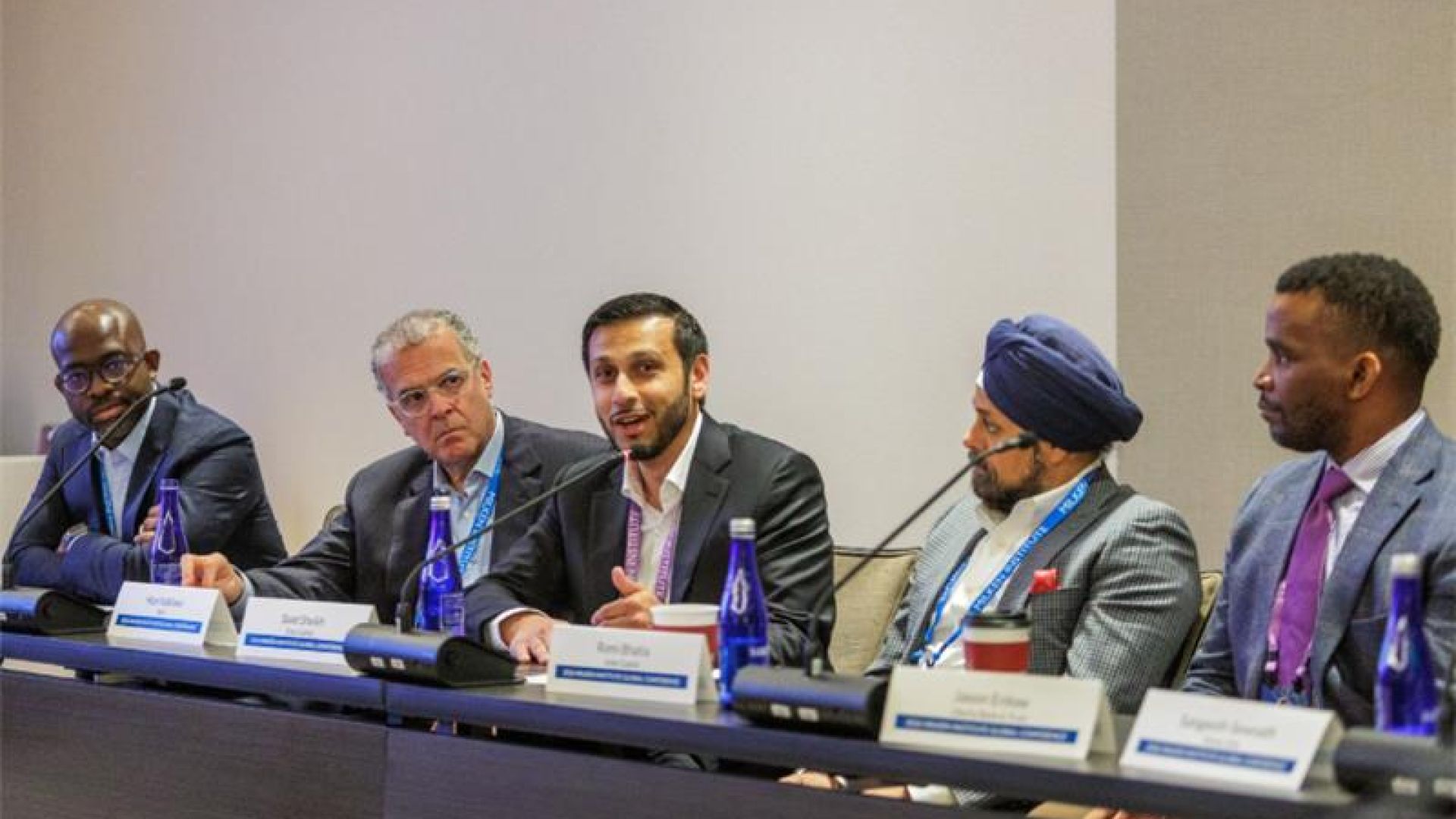 Five professionals seated at a conference table during a panel discussion